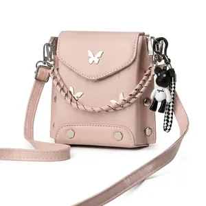 Detail view of pink vertical crossbody phone bag with metal butterflies and bear charm