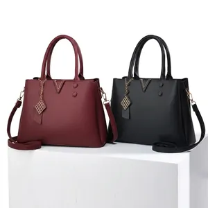 Detailed macro of burgundy litchi grain leather tote bag with elegant golden V hardware