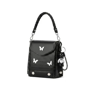 Close-up of black crossbody bag with white butterfly appliques and panda plush pendant