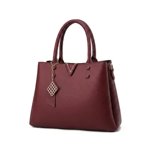 Detailed macro view of wine red litchi texture leather handbag with gold metal hardware