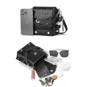 Macro view of compact black crossbody bag capacity with phone, sunglasses and cosmetics
