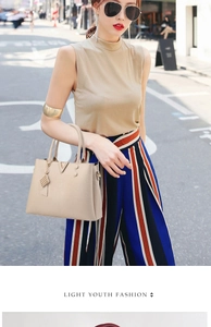 Detail of beige lychee pattern PU leather handbag with V-shaped metal clasp and tassel