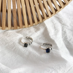 Detail of vintage silver rings with black onyx and blue gemstones in chain design