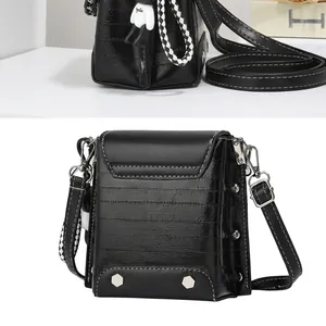 Side view of black mini crossbody bag with white contrast stitching and checkered strap