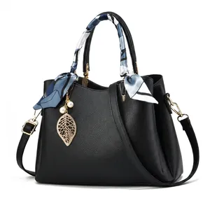 Détail du sac à main en cuir texturé avec poignée en foulard de soie et pendentif perle