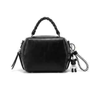 Detail of black hexagonal crossbody bag featuring white stitching and woven handle strap