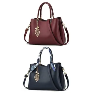 Détail de sacs en cuir texturé litchi avec foulard en soie et pendentif perle en feuille