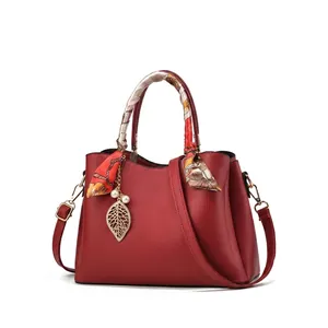 Vue détaillée du sac à main rouge en cuir PU avec anse en soie et pendentif feuille