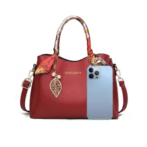 Détail du sac à main rouge en cuir grainé avec anse en soie et compartiments internes