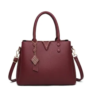 Detail of lychee pattern leather tote bag with V-shaped metal trim and tassel accent