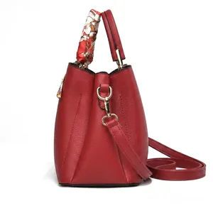 Détail du sac à main rouge en cuir grainé avec foulard en soie et finitions dorées
