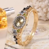 Macro shot of a vintage gold floral bangle watch with colorful crystal accents and quartz dial
