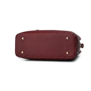 Detail of burgundy lychee leather bag base with four golden protective metal studs