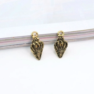 Detail shot of vintage gold conch shell charms for DIY jewelry making on white background