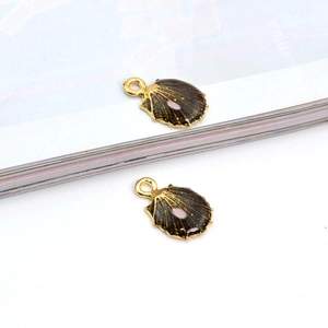 Details von zwei goldenen Muschel-Anhängern mit brauner Emaille und Pailletten