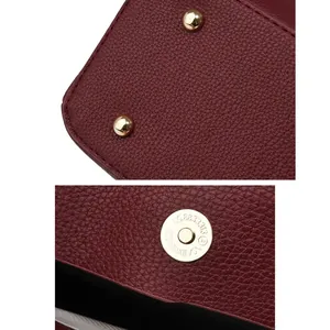 Detail of red litchi leather bag showing metal protective studs and magnetic buckle