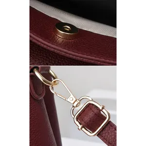 Close-up of wine red lychee pattern leather handbag with gold magnetic buckle and swivel hooks
