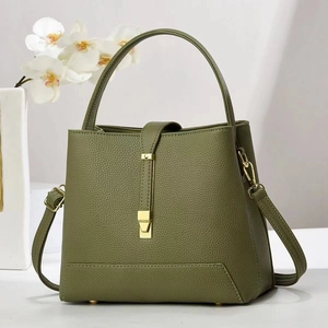 Detail of dark green lychee leather bucket bag with gold hardware and protective feet