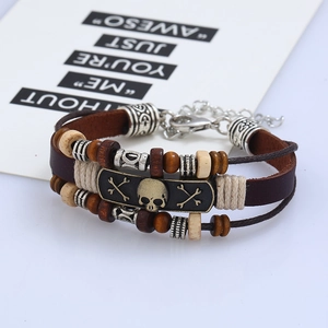 Detail of vintage leather bracelet featuring a bronze skull plate and layered beads