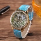 Detail of floral owl dial on gold watch case with blue leather strap on wood table