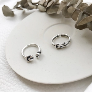 Detail view of retro S925 sterling silver knotted open rings on white ceramic plate