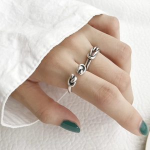 Detail of S925 sterling silver knotted ring on hand against a white leather background