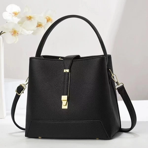 Detail shot of black litchi texture leather handbag with elegant gold metal hardware buckle