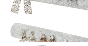 Detail view of rhinestone and pearl earrings on gray velvet jewelry display stand