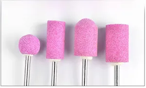Macro view of four different shapes of pink quartz stone nail drill bits for polishing