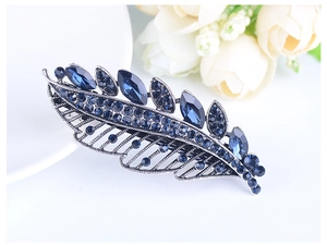 Detailed close-up of a blue crystal leaf-shaped hair clip with vintage silver finish