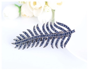 Macro shot of a feather-shaped hair clip with deep blue rhinestones on silver metal