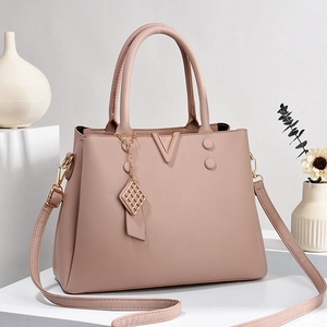 Elegant dusty pink pebbled leather handbag with gold V-shaped logo on white display stand