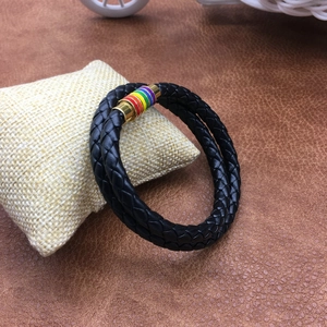 Close-up of black braided leather cord bracelet with rainbow magnetic clasp on beige pillow