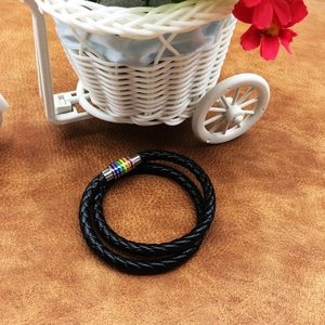 Macro detail of rainbow magnetic clasp on a black braided leather wrap bracelet