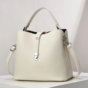 Détail de la texture litchi et des boucles en métal argenté sur le sac blanc crème