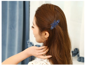 Detail of elegant dark blue butterfly hair claw clip with sparkling rhinestones on model