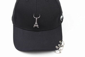 Dettaglio cappello punk nero con anelli in metallo e ciondolo torre Eiffel