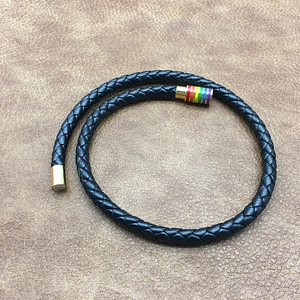 Close-up of black braided leather bracelet with golden rainbow enamel magnetic clasp