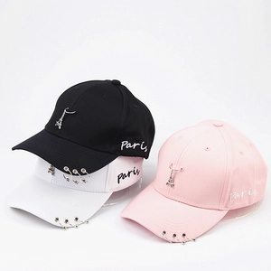Dettaglio di cappelli da baseball con anelli di metallo, ciondolo Torre Eiffel e ricamo