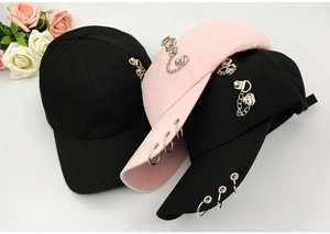 Detail of pink and black baseball caps with decorative metal rings and chains