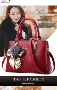 Detail of red faux leather tote bag with lychee texture, silk scarf, and pompom charm