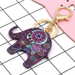 Detail of purple acrylic elephant keychain with colorful floral patterns and gold lobster clasp