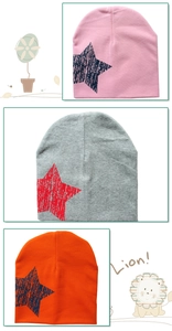 Close-up of three knitted beanies with star prints in pink, grey and orange colors