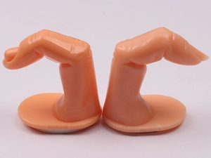 Detail view of two plastic flesh-colored manicure practice fingers on a white background
