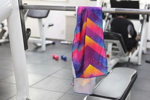 Detail of colorful geometric pattern cooling towel hanging on a gym equipment bar