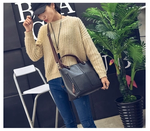 Dark grey PU leather tote bag with brown handle worn by a model in a casual setting