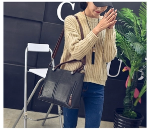 Detailed view of black PU leather tote bag with dual front zippers and brown strap on model