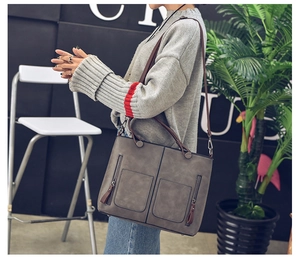 Detail of grey vintage oil leather tote bag featuring double straps and front zip pockets