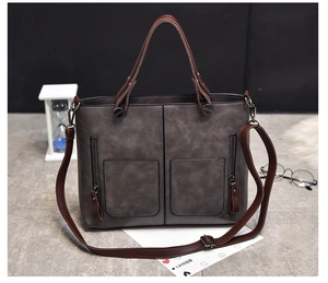 Detail of grey vintage leather tote bag featuring dual front zipper pockets and top handles
