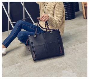 Close-up of black retro oil leather tote bag with dual zipper pockets and brown straps